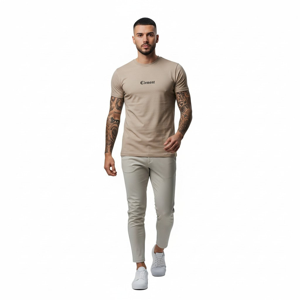 Vallmountbotique men's beige crew neck t-shirt with black text logo and slim fit light grey trousers.