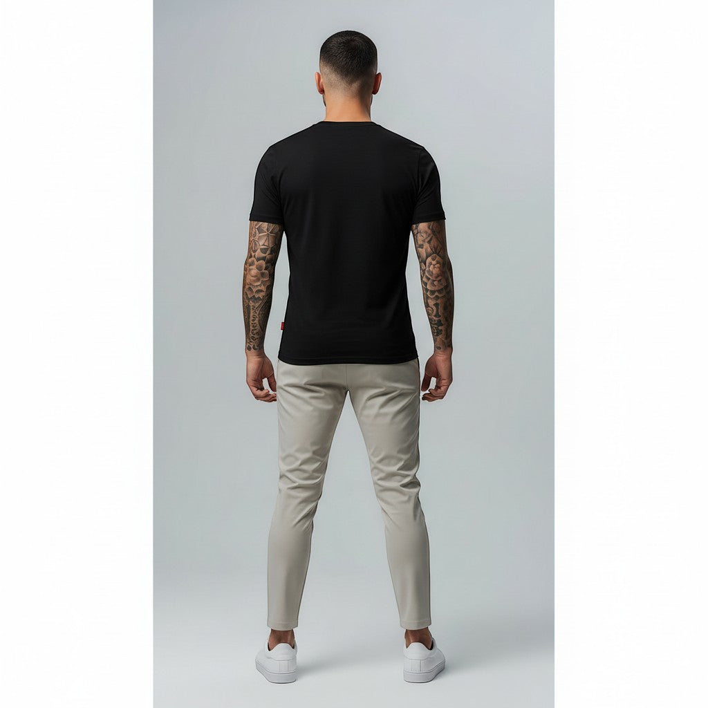 Vallmountbotique black cotton t-shirt with embroidered geometric logo on chest, worn by a man with tattoos.
