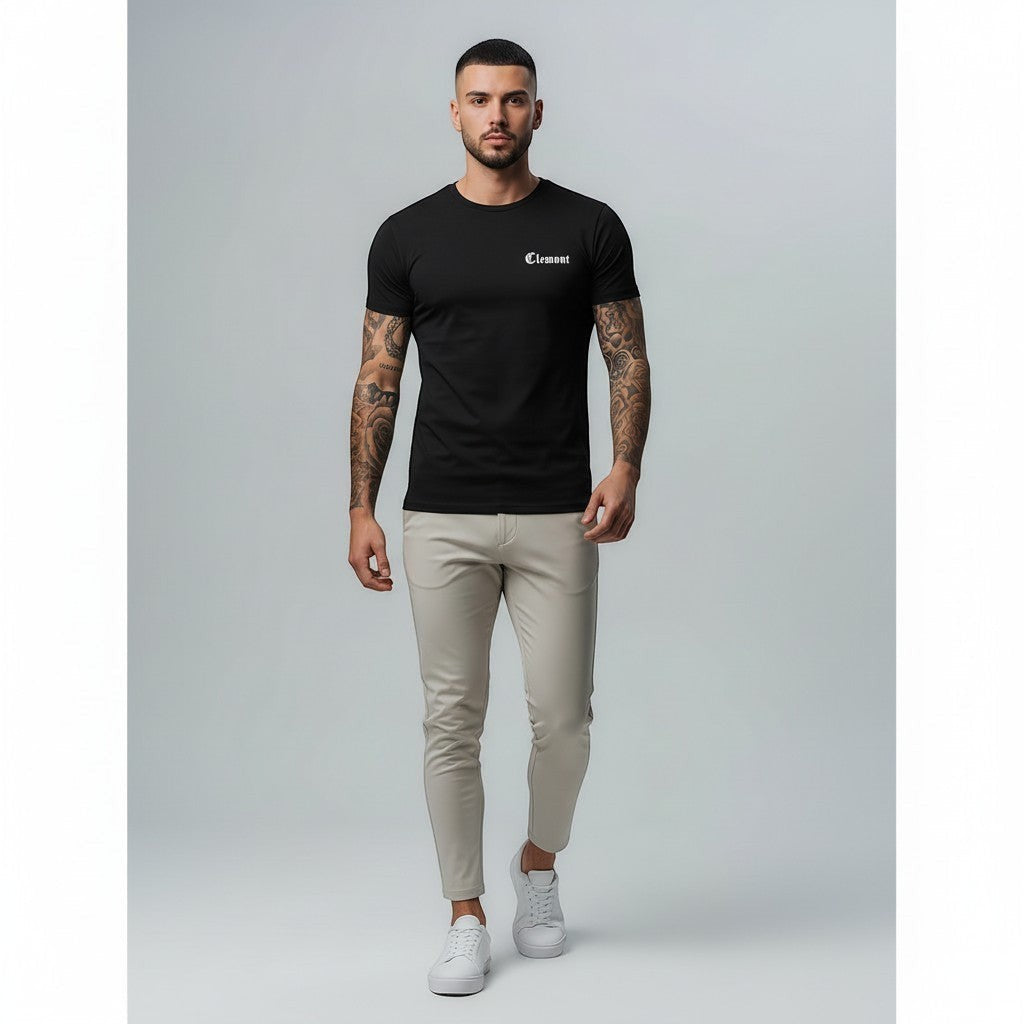 Vallmountbotique black cotton t-shirt with embroidered logo on chest and graphic print on back. Model wearing slim fit beige trousers and white sneakers.