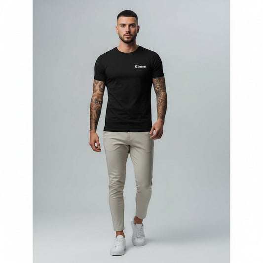 Vallmountbotique black cotton t-shirt with embroidered logo on chest and graphic print on back. Model wearing slim fit beige trousers and white sneakers.