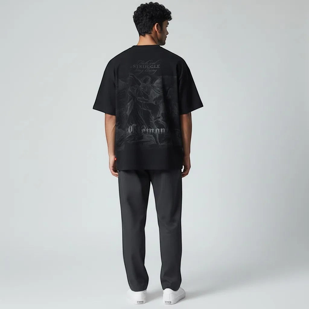 Vallmountbotique black oversized cotton t-shirt with a monochromatic graphic print of angels and the quote "Faith and Struggle Bring Blessing."