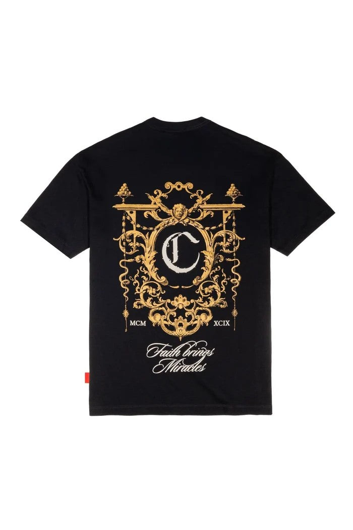 Vallmountbotique black cotton t-shirt with ornate gold crest graphic on back and chest, featuring MCM, XCIX, and "Faith Brings Miracles" text.