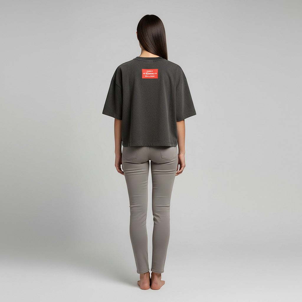 Vallmountbotique dark grey oversized t-shirt with red logo tag on back, worn by a woman in grey skinny jeans.