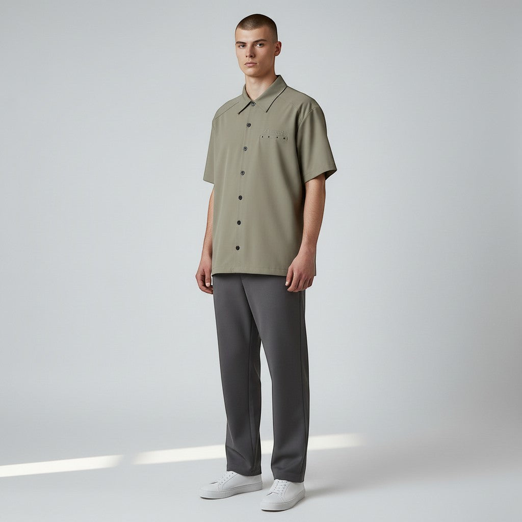 Vallmountbotique khaki short sleeve button-up shirt with embroidered logo on chest pocket and grommets on back yoke.