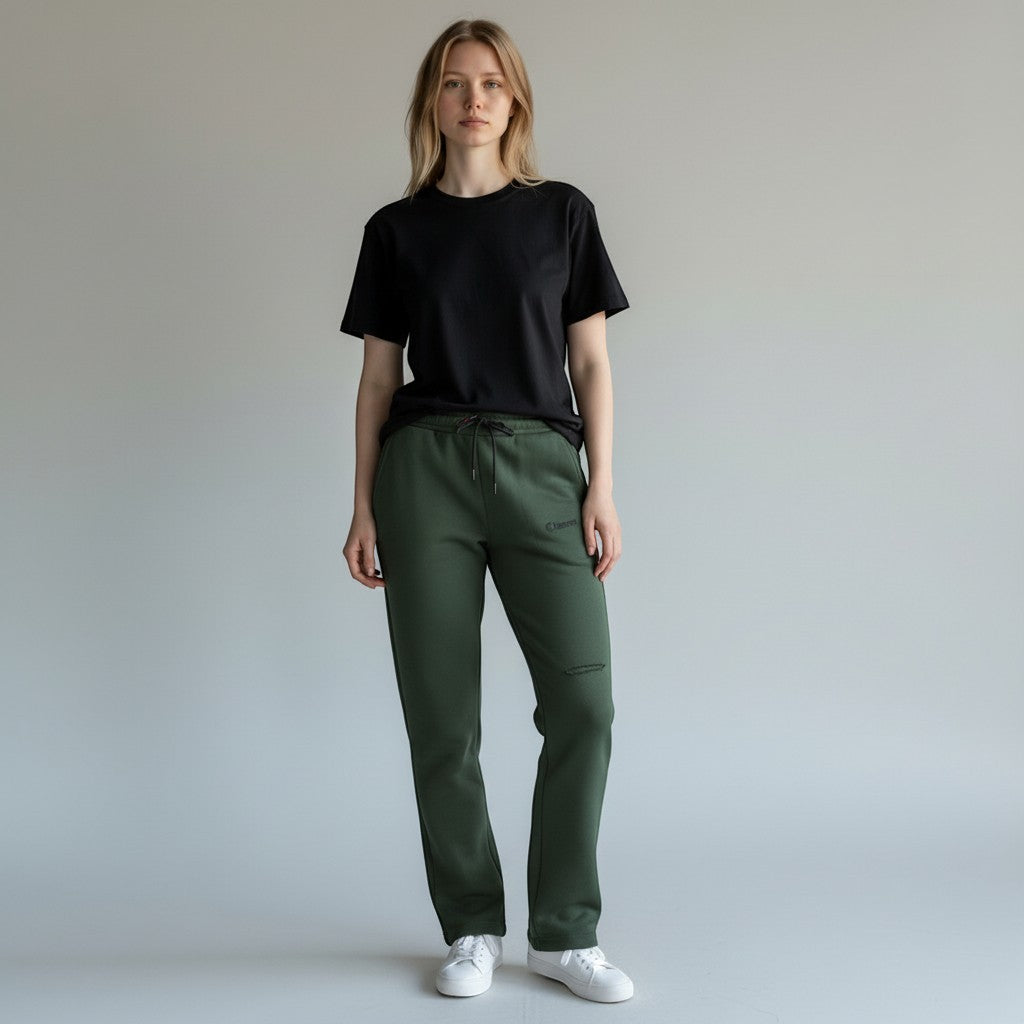 Vallmountbotique olive green relaxed fit sweatpants with drawstring waist and embroidered logo. Model wears black t-shirt and white sneakers.